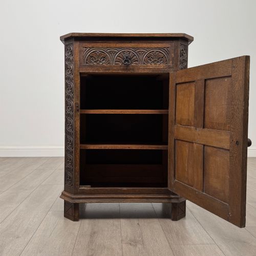 fig 1. A small dark oak cupboard featuring a single carved top drawer above a panelled cupboard door with iron hinges.
