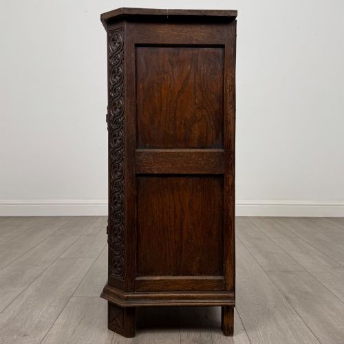 fig 3. A small dark oak cupboard featuring a single carved top drawer above a panelled cupboard door with iron hinges.