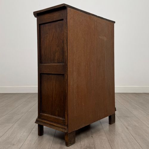 fig 4. A small dark oak cupboard featuring a single carved top drawer above a panelled cupboard door with iron hinges.