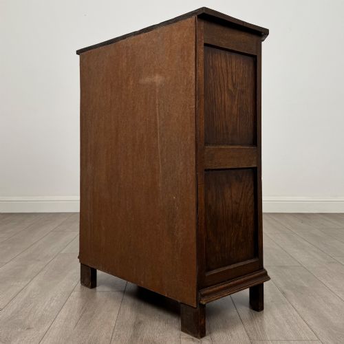 fig 6. A small dark oak cupboard featuring a single carved top drawer above a panelled cupboard door with iron hinges.