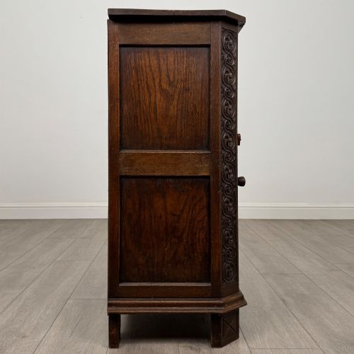 fig 7. A small dark oak cupboard featuring a single carved top drawer above a panelled cupboard door with iron hinges.