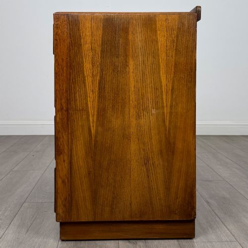 fig 2. An antique golden oak chest of four drawers fitted with decorative brass drop handles on a plinth base.