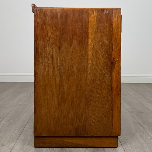 fig 6. An antique golden oak chest of four drawers fitted with decorative brass drop handles on a plinth base.