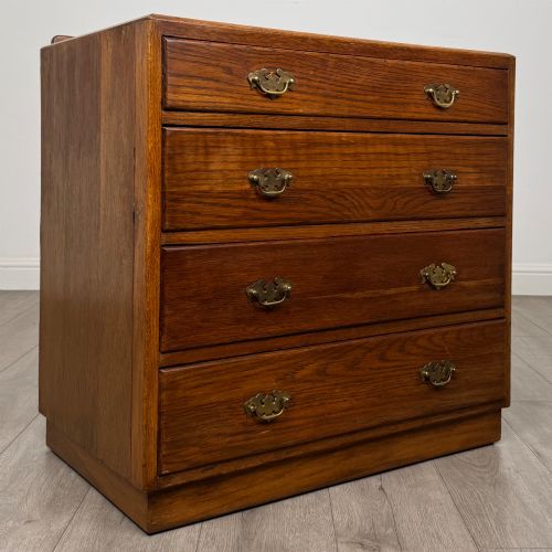 fig 7. An antique golden oak chest of four drawers fitted with decorative brass drop handles on a plinth base.