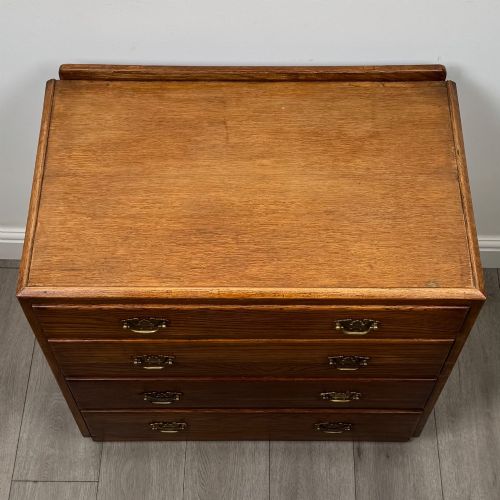 fig 8. An antique golden oak chest of four drawers fitted with decorative brass drop handles on a plinth base.