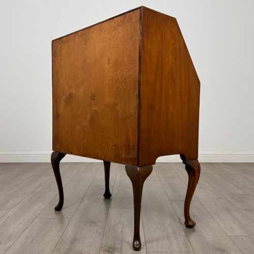 fig 6. An antique Edwardian burr walnut slant-front bureau featuring two drawers with metal handles, supported by carved cabriole legs.
