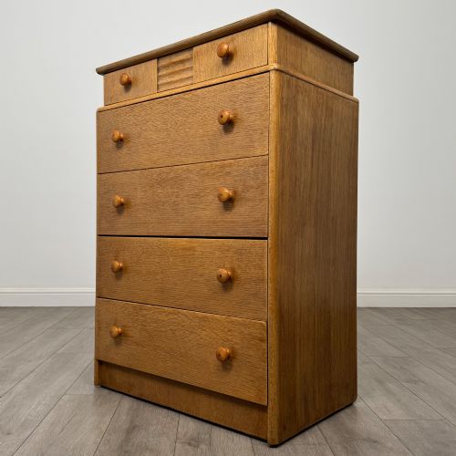 fig 1. A twentieth-century oak chest featuring four large horizontal drawers below two smaller upper drawers with turned wooden handles and a central carved fluted detail.