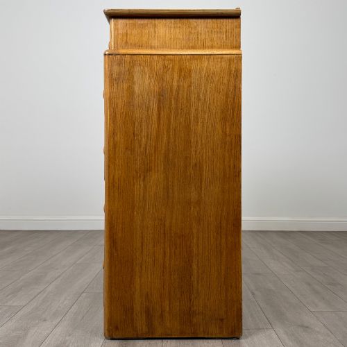 fig 2. A twentieth-century oak chest featuring four large horizontal drawers below two smaller upper drawers with turned wooden handles and a central carved fluted detail.