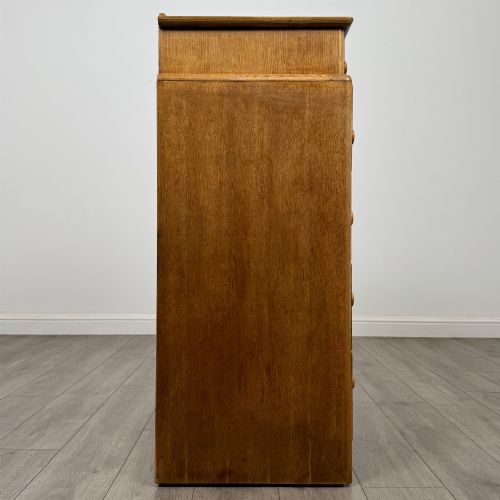 fig 6. A twentieth-century oak chest featuring four large horizontal drawers below two smaller upper drawers with turned wooden handles and a central carved fluted detail.