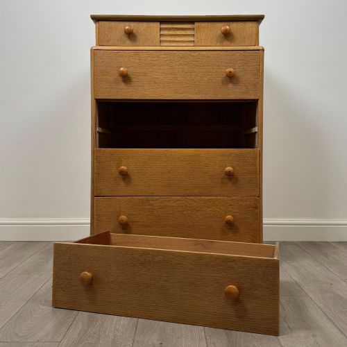 fig 9. A twentieth-century oak chest featuring four large horizontal drawers below two smaller upper drawers with turned wooden handles and a central carved fluted detail.