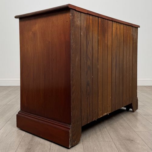 fig 3. An antique mahogany chest of drawers featuring two short top drawers over two long lower drawers with decorative metal handles on a plinth base.