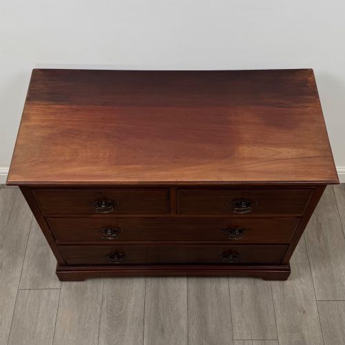 fig 8. An antique mahogany chest of drawers featuring two short top drawers over two long lower drawers with decorative metal handles on a plinth base.