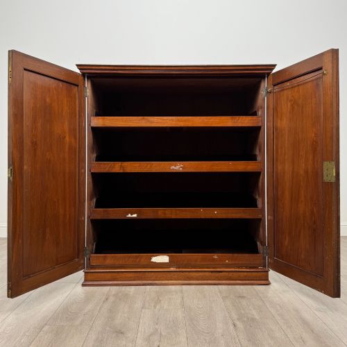 fig 1. An antique early twentieth-century two-door walnut linen cupboard featuring double panelled doors, a moulded top cornice, and a central brass teardrop handle.