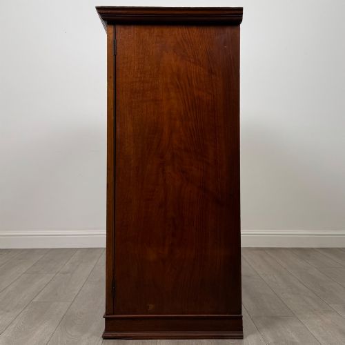 fig 3. An antique early twentieth-century two-door walnut linen cupboard featuring double panelled doors, a moulded top cornice, and a central brass teardrop handle.