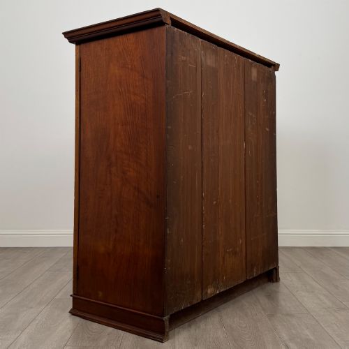 fig 4. An antique early twentieth-century two-door walnut linen cupboard featuring double panelled doors, a moulded top cornice, and a central brass teardrop handle.