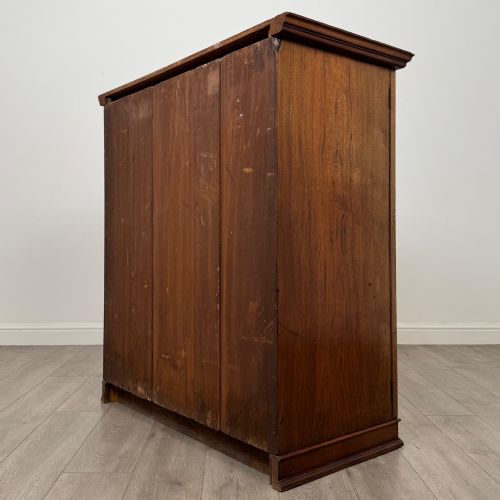 fig 6. An antique early twentieth-century two-door walnut linen cupboard featuring double panelled doors, a moulded top cornice, and a central brass teardrop handle.