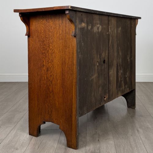 fig 4. An Arts and Crafts golden oak sideboard featuring two top drawers, two lower cupboard doors, and stylized copper strap hinges.