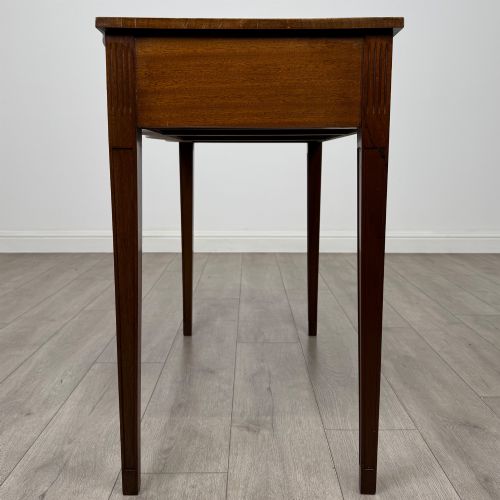 fig 2. A 20th-century burr walnut side table featuring a serpentine front, three drawer fronts with brass handles, and square tapered legs.