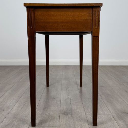 fig 6. A 20th-century burr walnut side table featuring a serpentine front, three drawer fronts with brass handles, and square tapered legs.