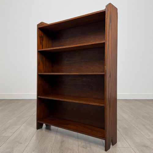 fig 2. An Edwardian dark oak open bookcase featuring four fixed shelves and shaped side panels.
