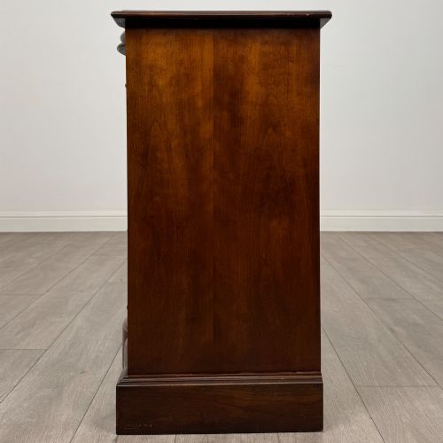 fig 2. A 20th-century serpentine-front hardwood chest featuring four stacked drawers with brass drop ring handles and central brass escutcheons.