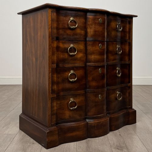 fig 7. A 20th-century serpentine-front hardwood chest featuring four stacked drawers with brass drop ring handles and central brass escutcheons.