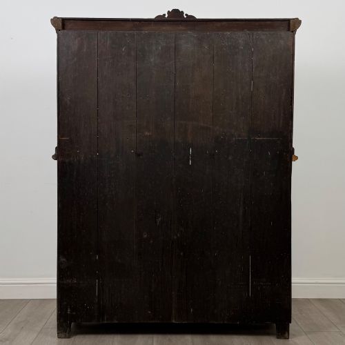 fig 5. A 19th-century dark oak carved cupboard featuring an open top shelf, carved lion cresting, relief-carved panel doors with figures, and an open lower base.
