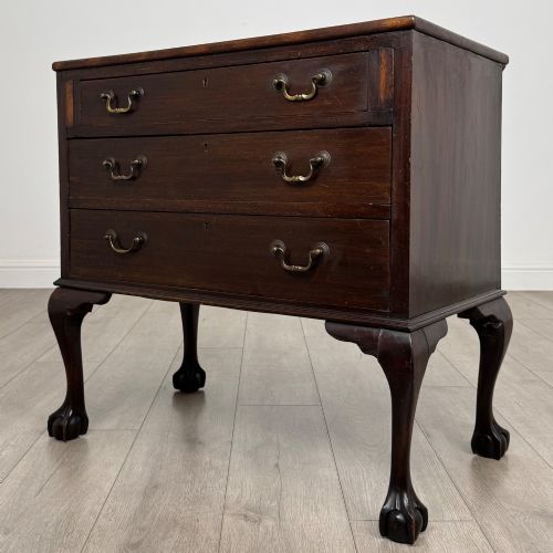 fig 1. A dark mahogany chest of drawers featuring three long drawers with brass handles, raised on carved cabriole legs ending in ball and claw feet.