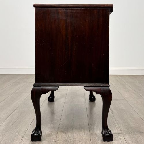 fig 2. A dark mahogany chest of drawers featuring three long drawers with brass handles, raised on carved cabriole legs ending in ball and claw feet.