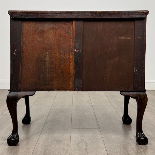 fig 4. A dark mahogany chest of drawers featuring three long drawers with brass handles, raised on carved cabriole legs ending in ball and claw feet.