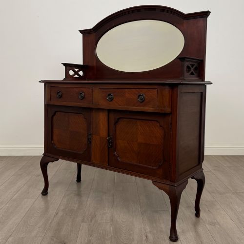 fig 2. An antique Edwardian mahogany sideboard featuring a top section with a central oval mirror, two drawers, and a two-door cabinet below raised on cabriole legs.