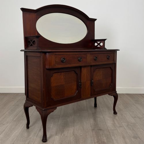 fig 8. An antique Edwardian mahogany sideboard featuring a top section with a central oval mirror, two drawers, and a two-door cabinet below raised on cabriole legs.