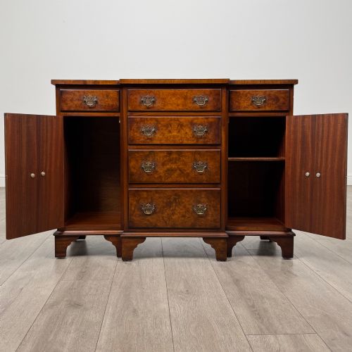 fig 1. An antique 20th-century small breakfront sideboard with figured burr walnut veneers, brass drop handles, four central drawers, and side cupboard doors.