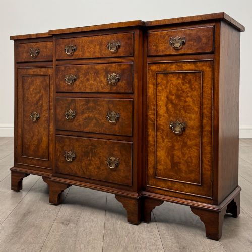 fig 2. An antique 20th-century small breakfront sideboard with figured burr walnut veneers, brass drop handles, four central drawers, and side cupboard doors.