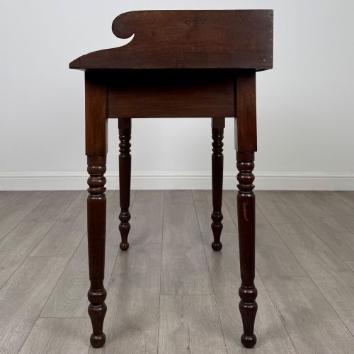 fig 2. A 19th-century dark mahogany writing table featuring a raised gallery back upstand, two frieze drawers with turned handles, and four turned legs.