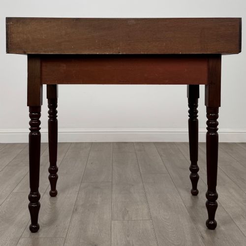 fig 4. A 19th-century dark mahogany writing table featuring a raised gallery back upstand, two frieze drawers with turned handles, and four turned legs.