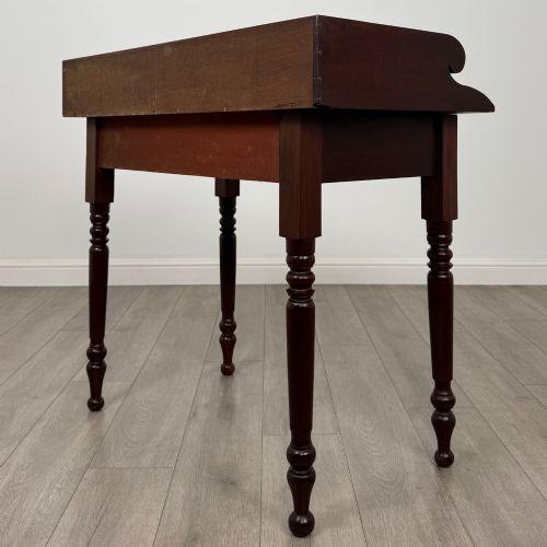 fig 5. A 19th-century dark mahogany writing table featuring a raised gallery back upstand, two frieze drawers with turned handles, and four turned legs.