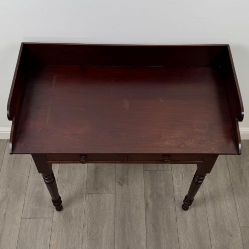 fig 8. A 19th-century dark mahogany writing table featuring a raised gallery back upstand, two frieze drawers with turned handles, and four turned legs.