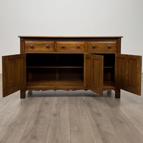 fig 1. A warm brown solid oak sideboard with three drawers positioned above three fielded panel cupboard doors.