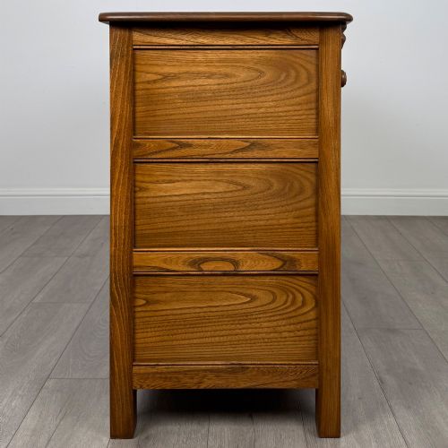 fig 7. A warm brown solid oak sideboard with three drawers positioned above three fielded panel cupboard doors.