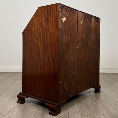 fig 4. An 18th-century Georgian mahogany bureau featuring a sloped fall-front lid, brass batwing handles and escutcheons, three graduated drawers, and bracket feet.