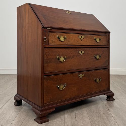 fig 8. An 18th-century Georgian mahogany bureau featuring a sloped fall-front lid, brass batwing handles and escutcheons, three graduated drawers, and bracket feet.