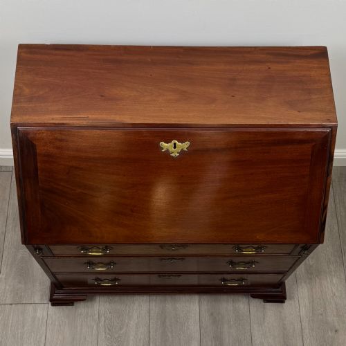 fig 9. An 18th-century Georgian mahogany bureau featuring a sloped fall-front lid, brass batwing handles and escutcheons, three graduated drawers, and bracket feet.