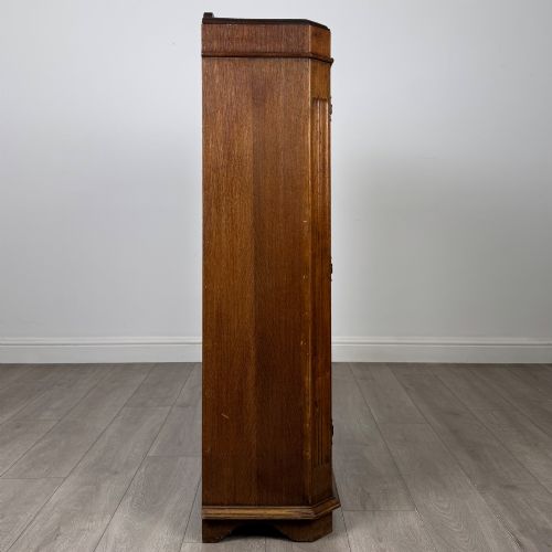 fig 7. A twin-door dark oak display cabinet featuring leaded glass upper panels, carved decorative lower panels, and ornate metal hinges.