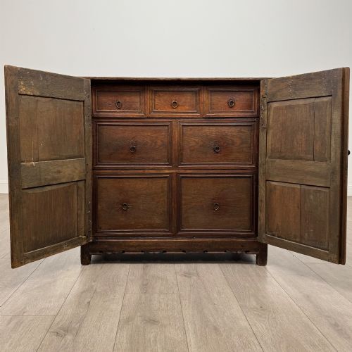 fig 1. A seventeenth-century oak cupboard featuring two panelled doors with moulded trim and hand-forged iron hinges.