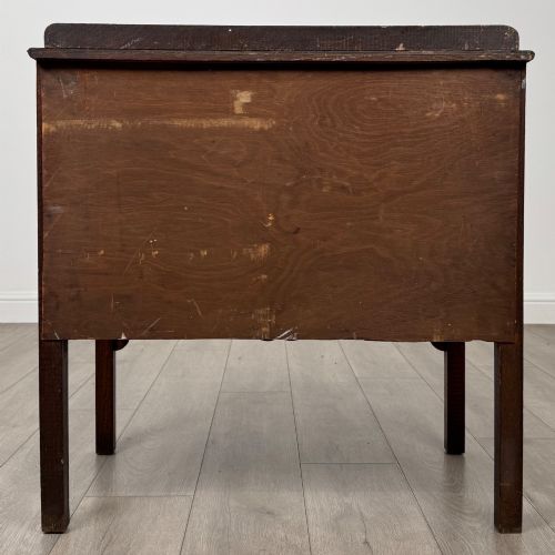 fig 4. An antique golden oak chest of drawers featuring two wide drawers with stylised dark metal handles and a scalloped lower apron.