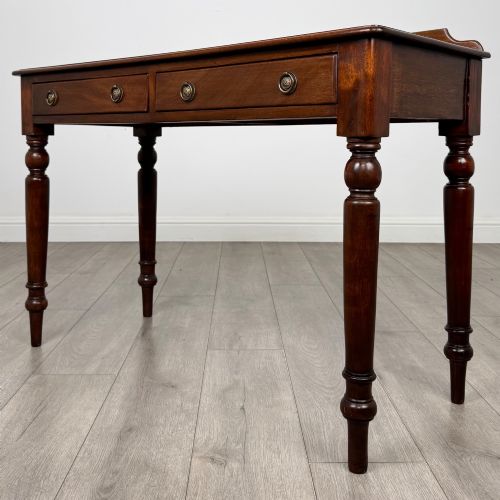 fig 1. A Victorian mahogany writing table featuring two frieze drawers with brass ring handles and four turned legs.
