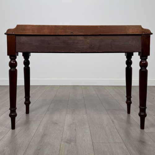 fig 4. A Victorian mahogany writing table featuring two frieze drawers with brass ring handles and four turned legs.