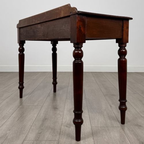 fig 5. A Victorian mahogany writing table featuring two frieze drawers with brass ring handles and four turned legs.