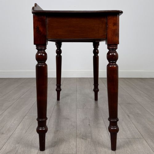 fig 6. A Victorian mahogany writing table featuring two frieze drawers with brass ring handles and four turned legs.